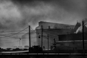 A black and white photograph showing smoke around the mill buildings