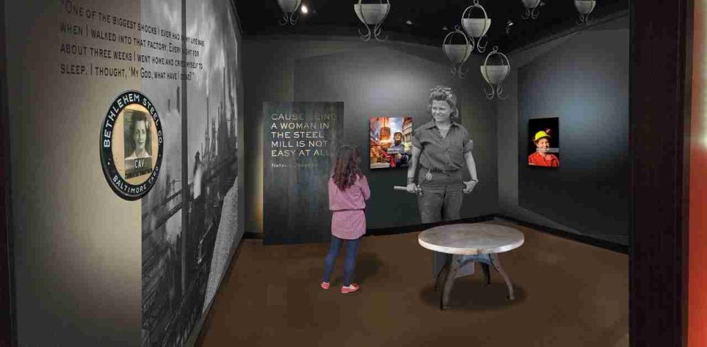An illustration shows an indoor gallery with dark walls, a table at the center, and photographs and text on the walls