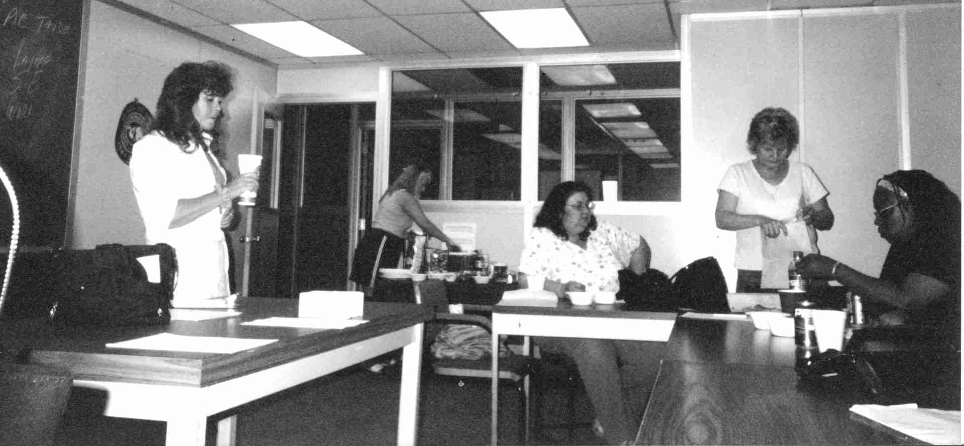A black and white photo shows five women meeting to discuss union issues.