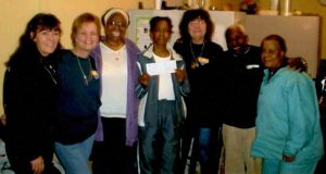 Seven women stand proudly with a check for the Bea Gaddy Foundation. 