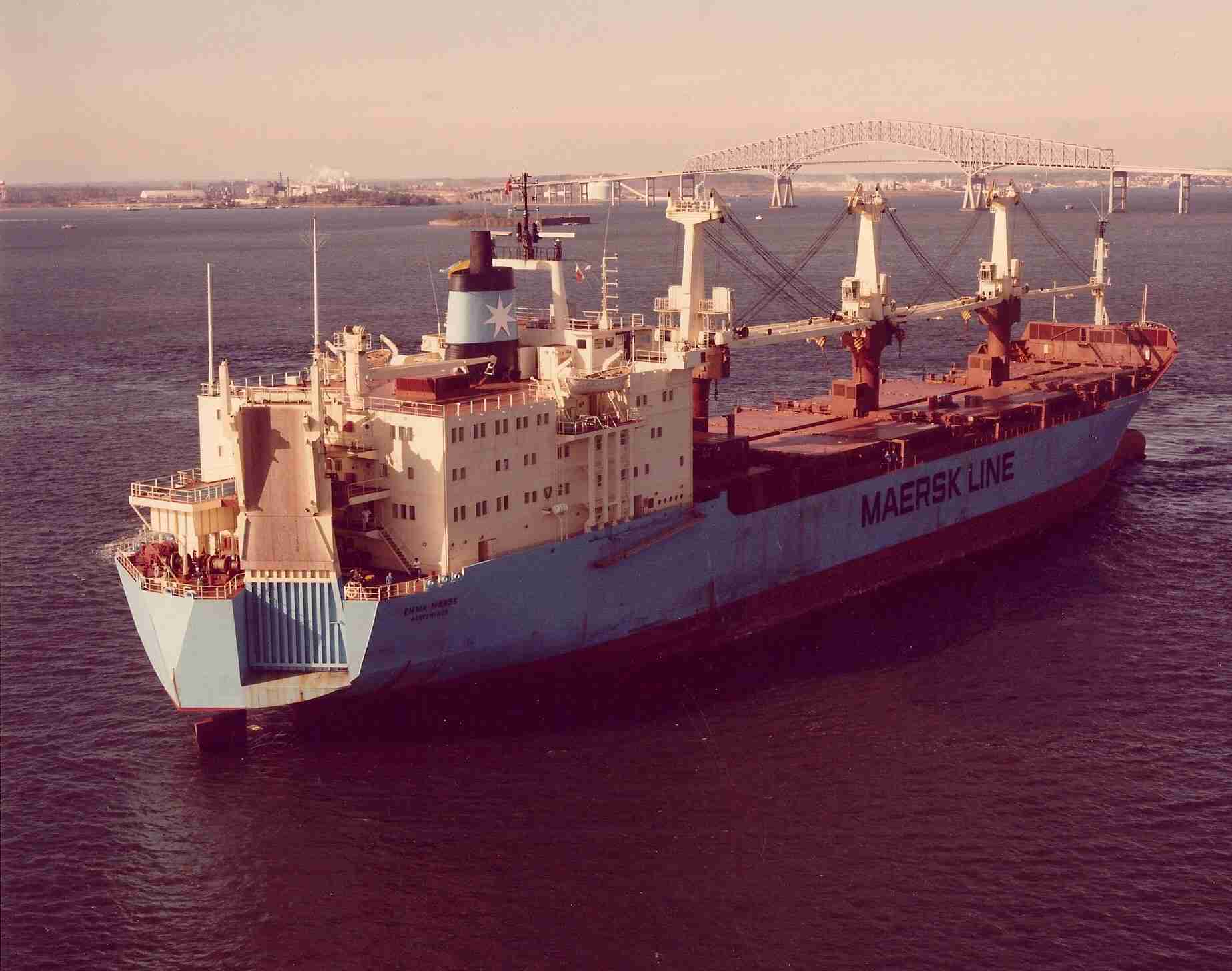 A vintage photo shows a large container ship with the Key Bridge in the background