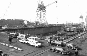 A black and white photo shows the building basin at the Sparrows Point shipyard, with a large crane overhead