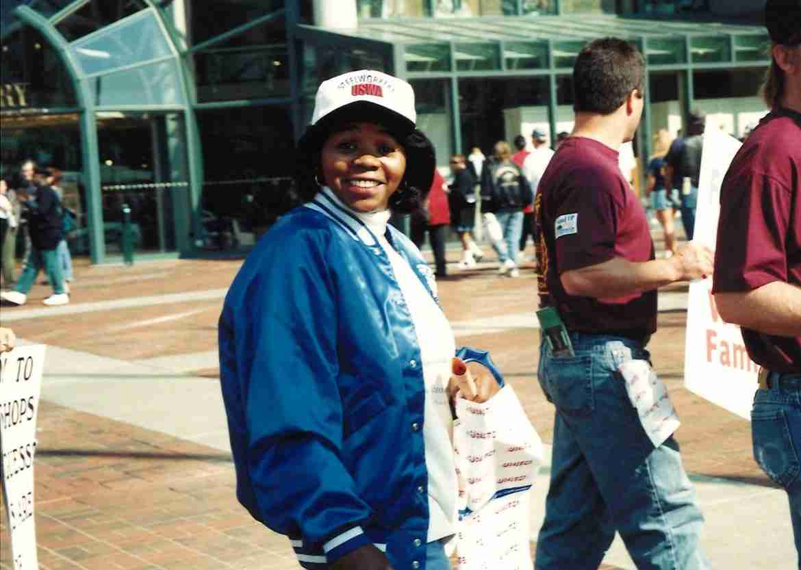 Color photo of Black woman in a blue jacket and a baseball cap.